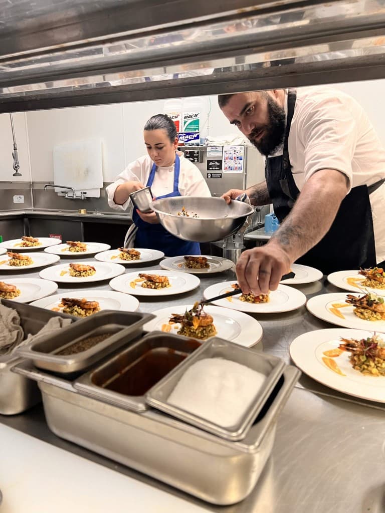 Nilani and Kachik plating shrimp dishes in a commercial kitchen