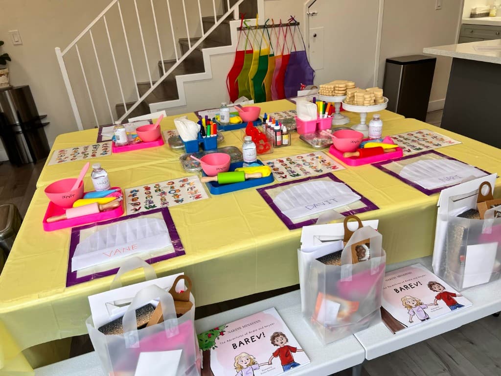 Kids cookie decorating class setup at home with named chef hats, rolling pins, and sprinkle stations